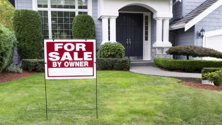 For Sale By Owner sign in front yard of home for sale.