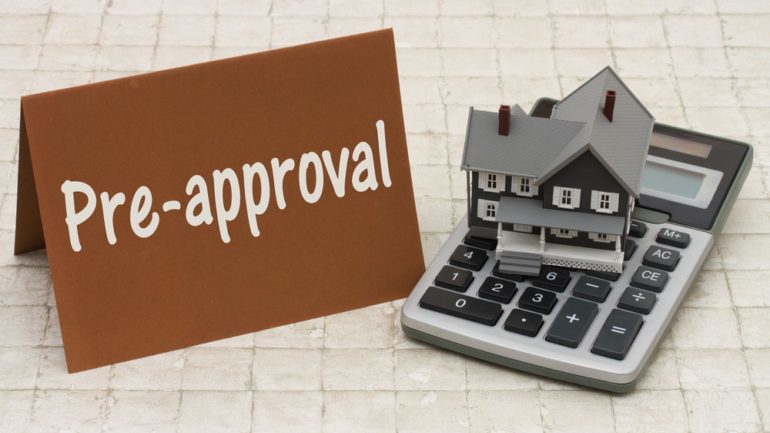 Sign showing the word preapproval with a home and calculator model to explain the process of being preapproved for purchasing a home.