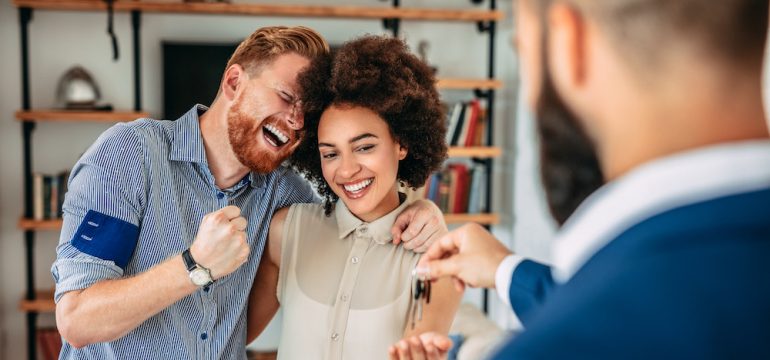 Real estate agent giving house keys to couple in their new home.