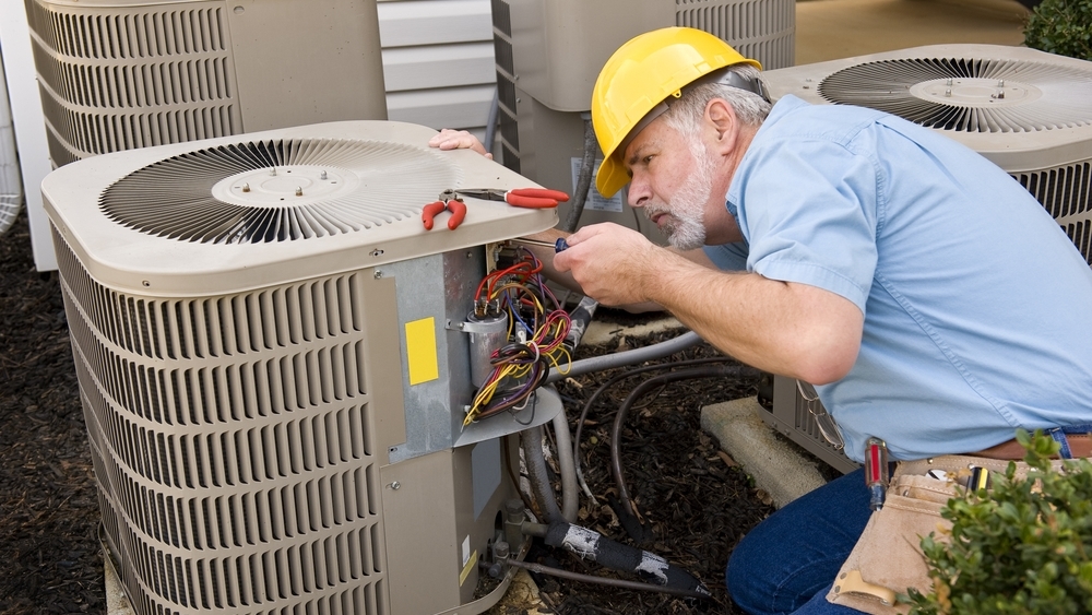 Service professional inspecting the compressor and other home HVAC systems