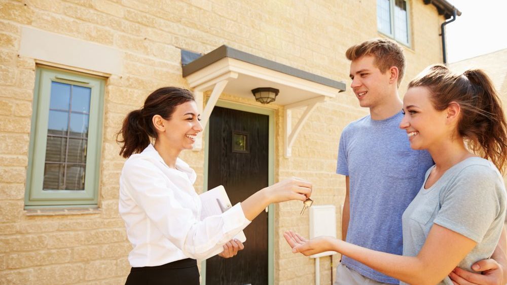 Female real estate agent giving keys to new property owners