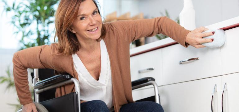 Beautiful woman in a wheelchair cleaning an accessible kitchen counter.