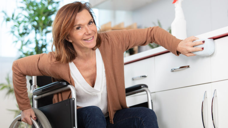 Beautiful woman in a wheelchair cleaning an accessible kitchen counter.