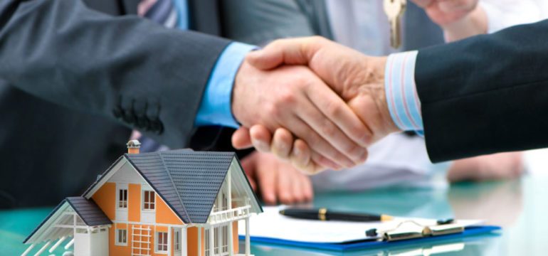 Estate agent shaking hands with customer after real estate contract signature.