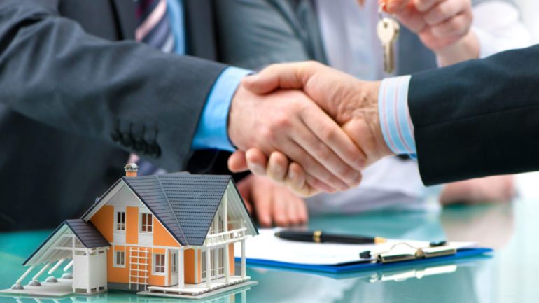 Estate agent shaking hands with customer after real estate contract signature.