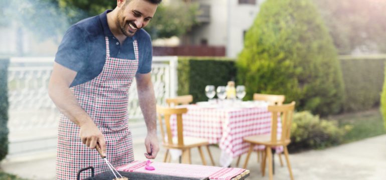 Man preparing barbecue in the backyard as part of his June To-Dos list.