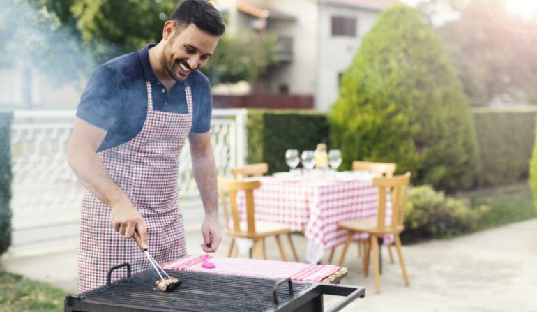 Man preparing barbecue in the backyard as part of his June To-Dos list.