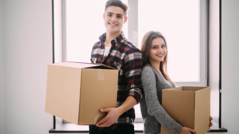 New home buyer couple holding boxes moving into their first home.