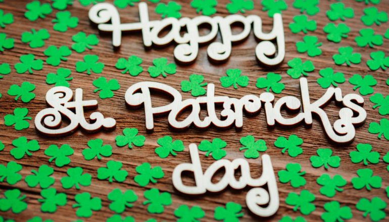 Happy St. Patrick's Day with shamrocks and wooden background