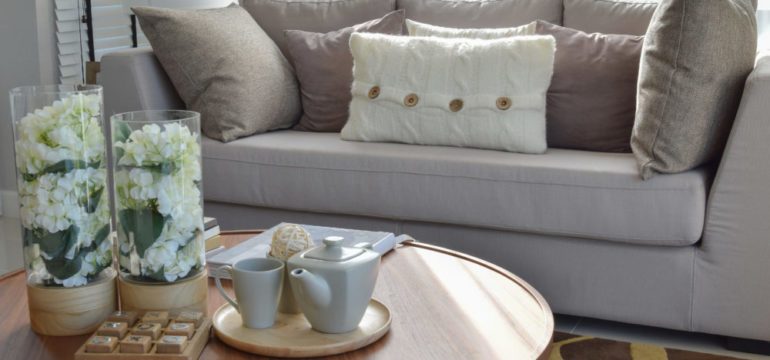 Home staging a living room with a decorative tea set and glass vase on wooden round table.