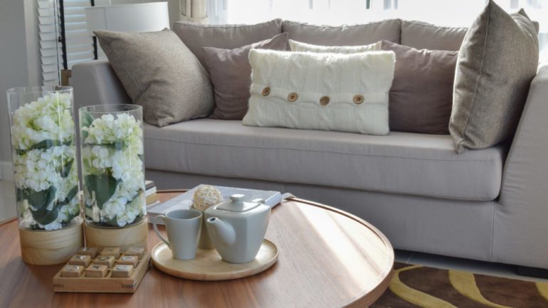 Home staging a living room with a decorative tea set and glass vase on wooden round table.