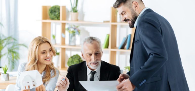 Professional baby boomer and millennial real estate agents feeling satisfied with the results of their work while looking at the important document.