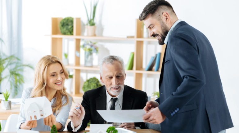 Professional baby boomer and millennial real estate agents feeling satisfied with the results of their work while looking at the important document.