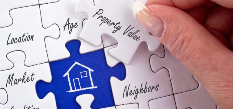 Property value and home equity puzzle with female hand placing piece in a real estate puzzle.