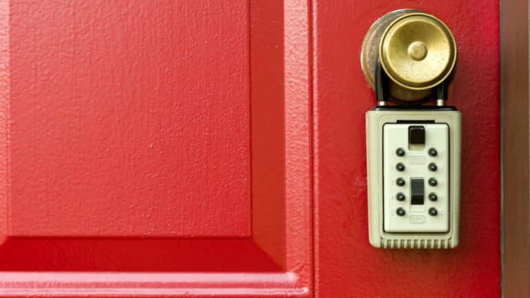 Concept of lockboxes on a house's red front door.