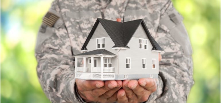 Photo of military officer holding a model of home in hands to represent military relocations.