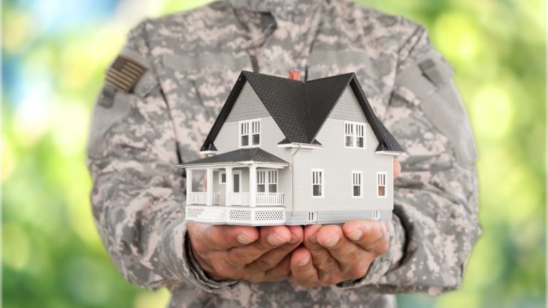 Photo of military officer holding a model of home in hands to represent military relocations.