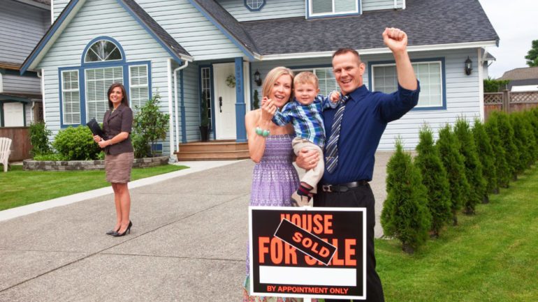 Selling your home takes teamwork. A young family celebrate selling a home working as a team with their real estate agent.