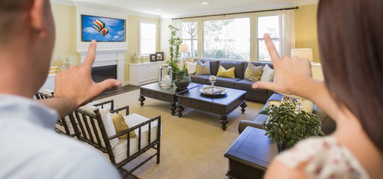 Young couple framing a living room with their hands considering a buying a home for resale value.