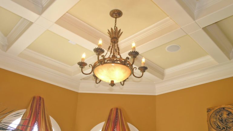 Luxury dining room with elegant coffered ceiling and light fixture.