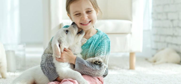 Little girl playing with her new dog at home.