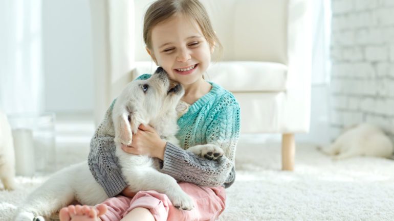 Little girl playing with her new dog at home.