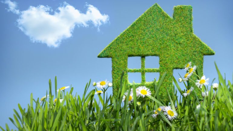 Green house built from grass against blue sky to represent concept of green building.