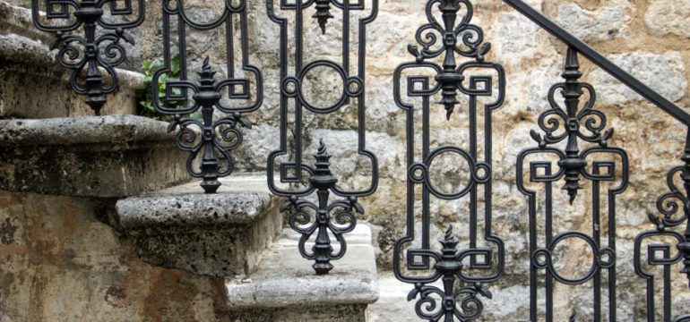 Elegant wrought iron bannister on outdoor steps of a stone front home.