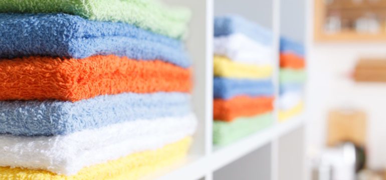 A multicolored stack of towels organized in a linen closet.
