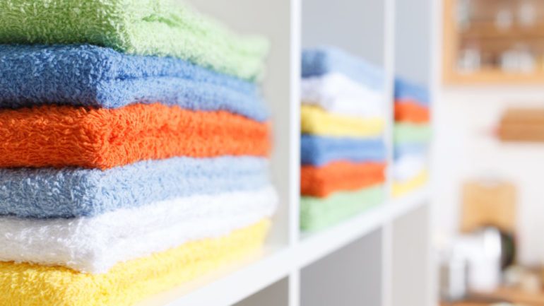 A multicolored stack of towels organized in a linen closet.