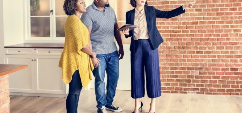 Couple discussing plans to buy a new home with their real estate agent. Wondering if you should buy a new home before selling yours.