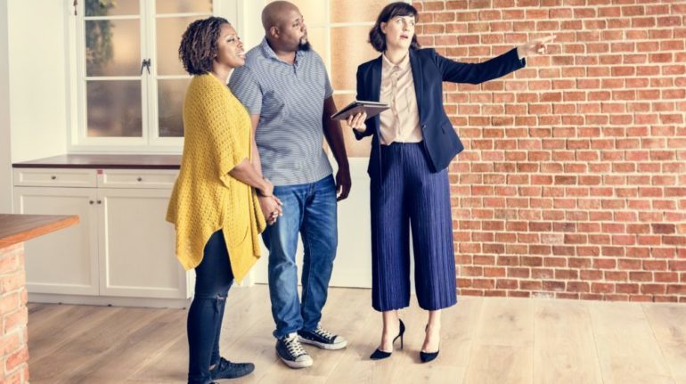 Couple discussing plans to buy a new home with their real estate agent. Wondering if you should buy a new home before selling yours.