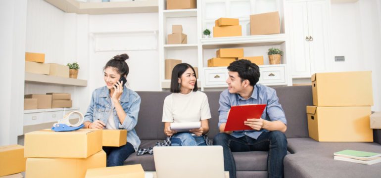 Young asian couple and friend preparing checklist for tasks to complete in their new home.