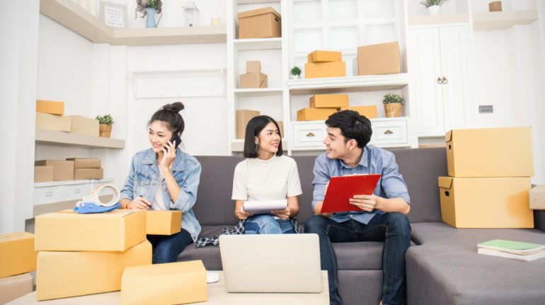 Young asian couple and friend preparing checklist for tasks to complete in their new home.