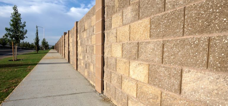 Stone block sound barrier built in neighborhood to block road noise.