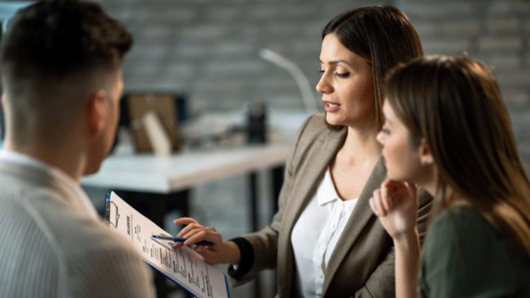 Female real estate agent talking to a couple while making plans about their future home purchase during a meeting in the office.