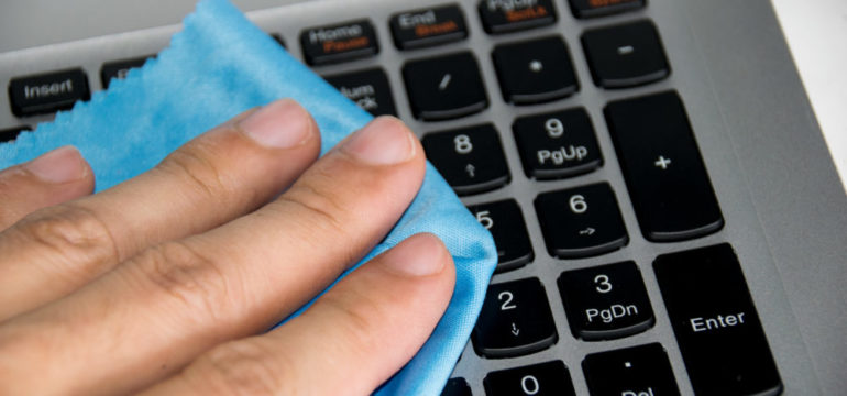 Close up holding blue wipes to clean your computer keyboard.