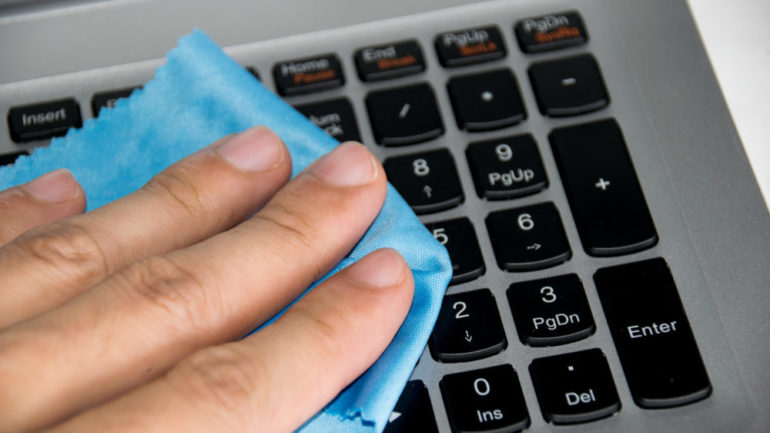 Close up holding blue wipes to clean your computer keyboard.