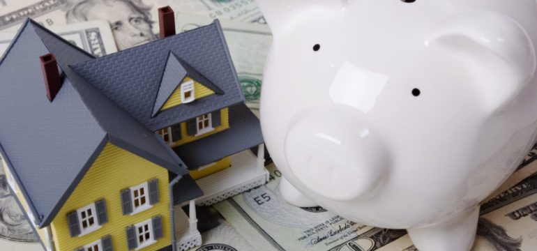 House with twenty dollar bills background and piggy bank for down payment assistance on a new home.