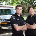 Portrait of two first responders or military standing in front of an ambulance.