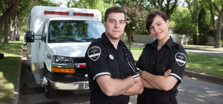 Portrait of two first responders or military standing in front of an ambulance.