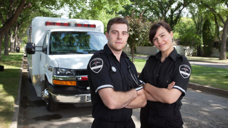 Portrait of two first responders or military standing in front of an ambulance.