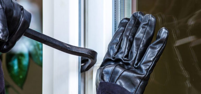 Photo of robber breaking into a window with a crowbar in a home without a security system.