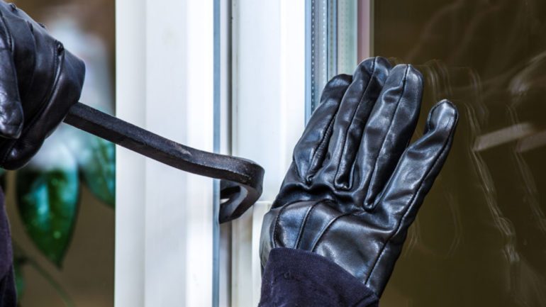 Photo of robber breaking into a window with a crowbar in a home without a security system.