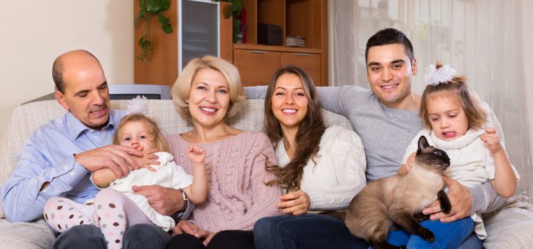 Portrait of big, happy multigenerational household with members sitting on sofa at home.