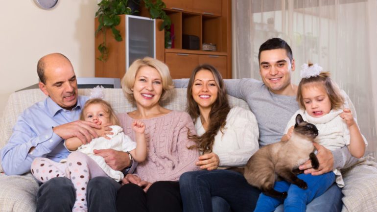 Portrait of big, happy multigenerational household with members sitting on sofa at home.