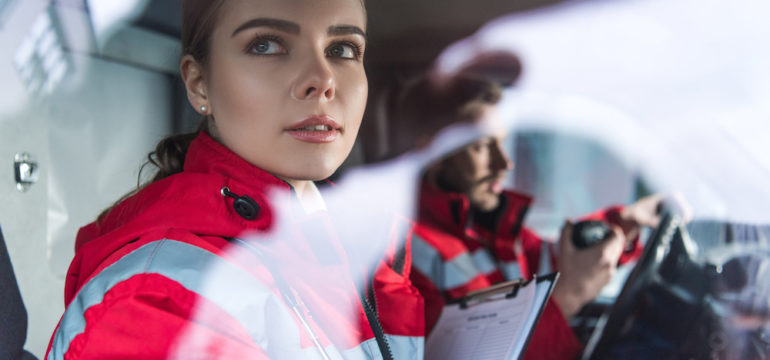 Female paramedic sitting in ambulance with clip board ready to gather patient medical information.