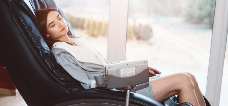 Young woman relaxing on a home massage chair.