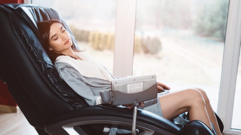 Young woman relaxing on a home massage chair.
