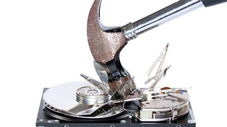 A computer hard drive being destroyed with a hammer for disposing of a computer.